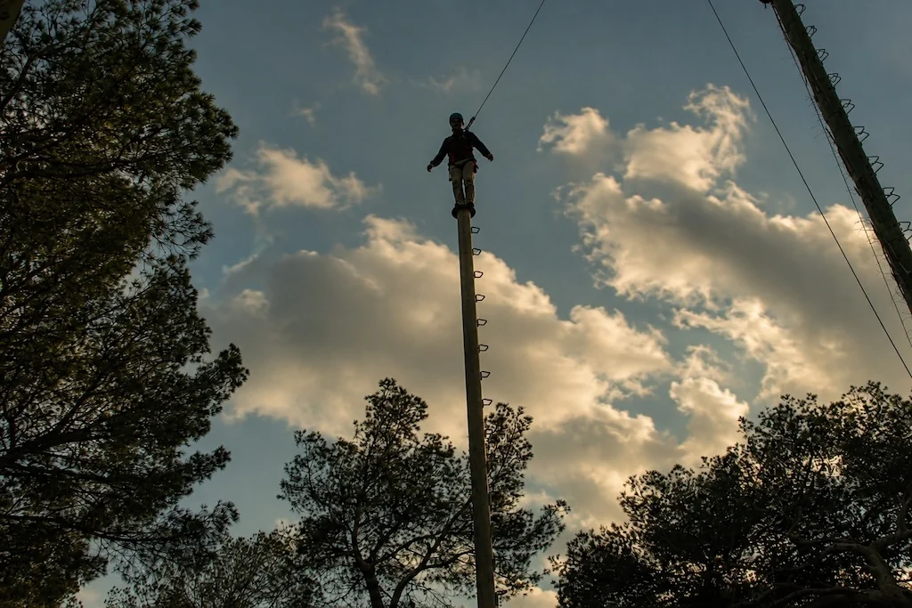 Participant standing on top of a pole